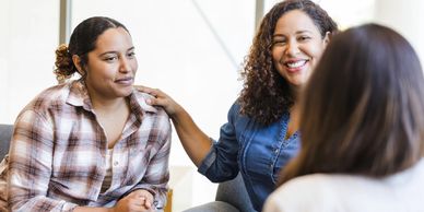Three women having a supportive conversation indoors.