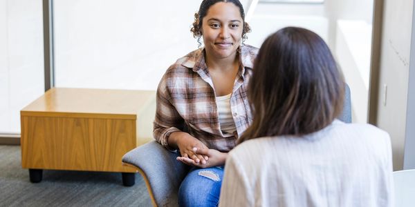 Two women having a conversation in a modern office setting.