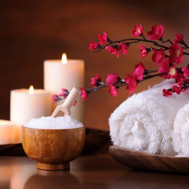 Spa setup with candles, towels, and bath salts with flowers.