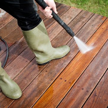 Person power washing a wooden deck 