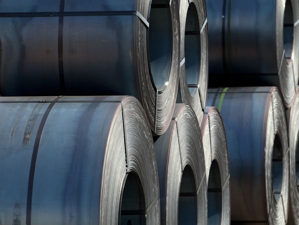 Stacks of coiled steel sheets bound with straps in an industrial setting.