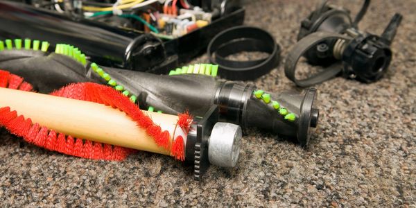 Disassembled vacuum cleaner parts on a carpet.