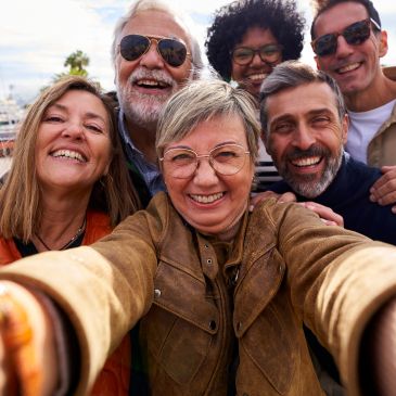 Group selfie with smiling diverse adults outdoors.
