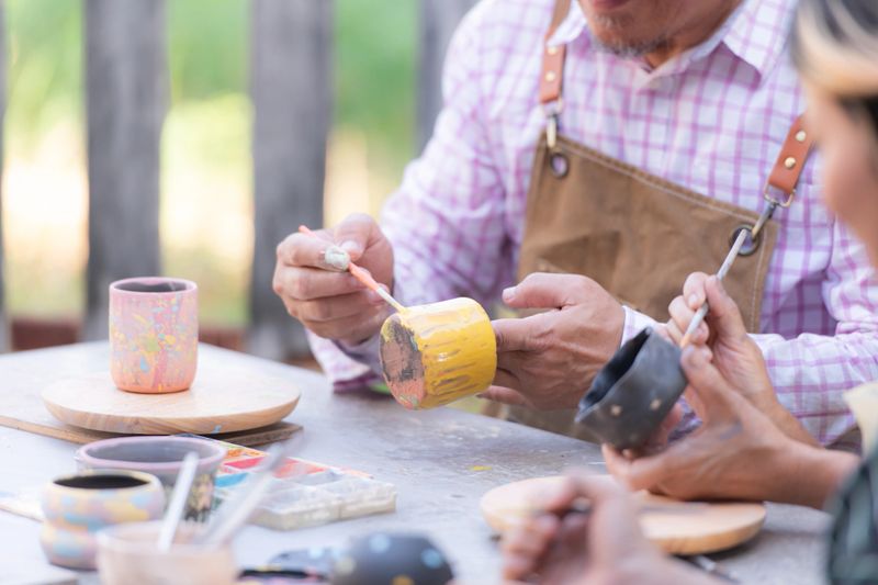 In the pottery workshop, an Asian retired couple is engaged in pottery making and clay painting activities.