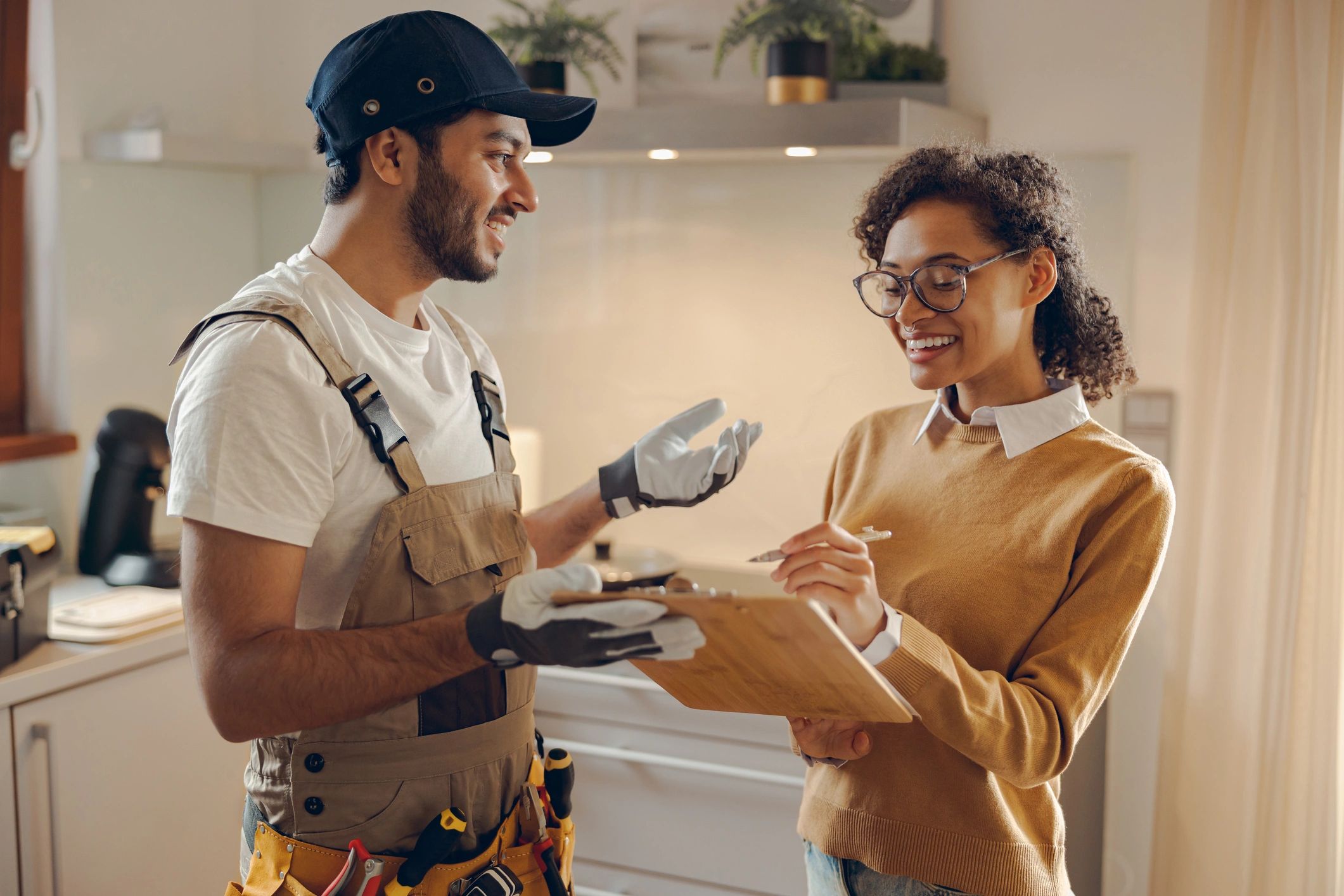 A contractor and woman happily discussing a clipboard in a kitchen.