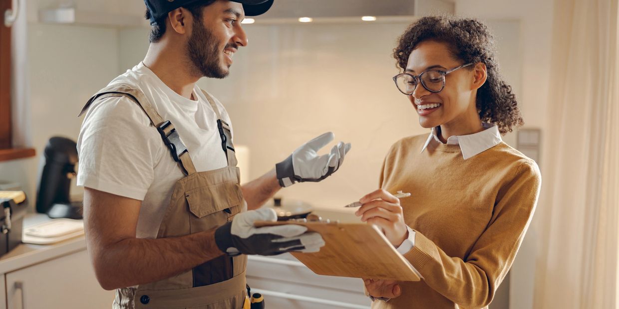 Technician and woman discussing work with clipboard indoors.