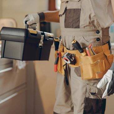 Handyman holding toolbox with tool belt.