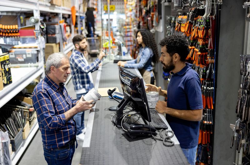 Latin American man shopping at the hardware store and talking to the retail clerk