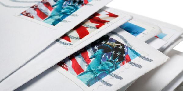 Stack of envelopes with Statue of Liberty stamps.