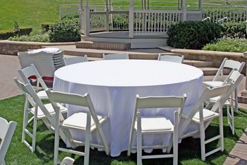 Round table with white chairs outdoors.