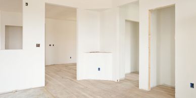 Empty room with light wooden flooring and white walls.