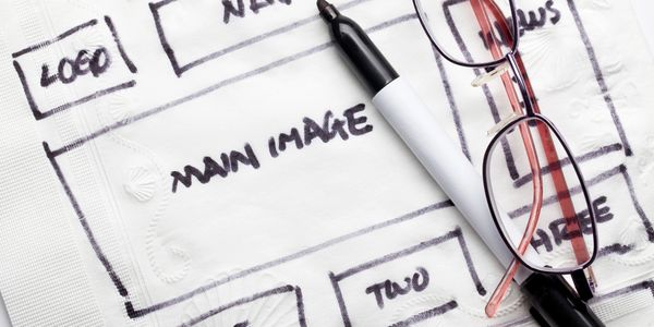 Skizze eines Webseiten-Layouts mit Marker und Brille – Konzeptentwicklung & Designplanung bei KMT Druckwelt.