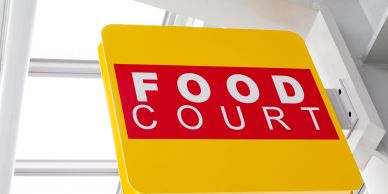 Bright yellow food court sign inside a building.