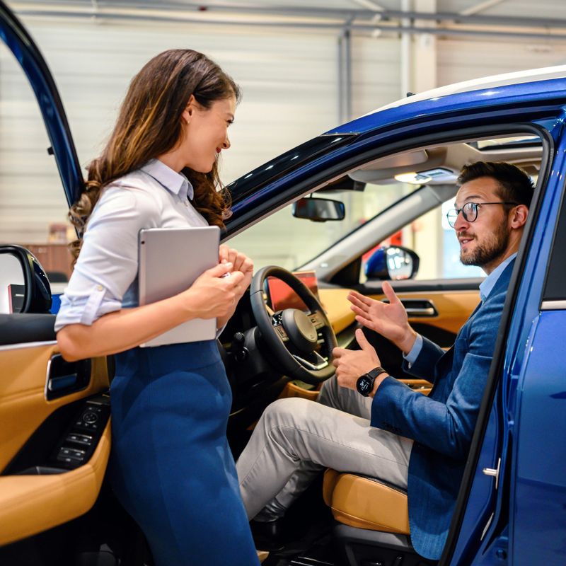 Saleswoman helping the male customer to choose a new car
