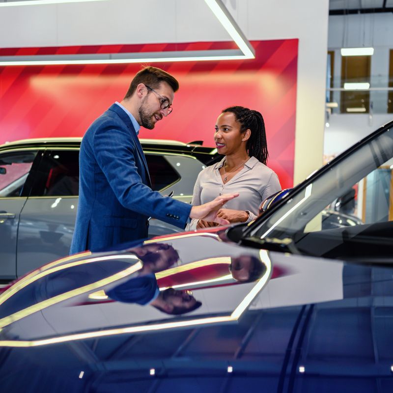 Salesman helping the female customer to choose a new car