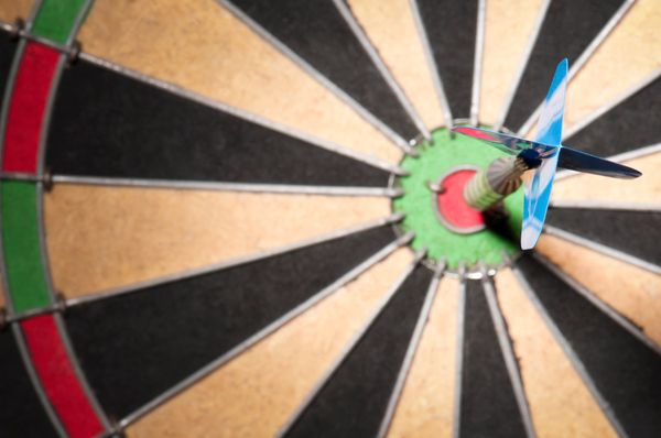 Dart hitting the bullseye on a dartboard.