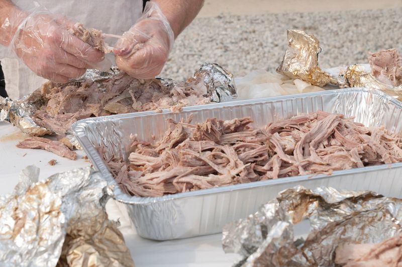 Hands pulling pork at a hog roast