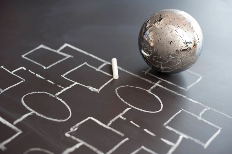 Diverse group of professionals discussing global business against a concrete wall featuring a green world map