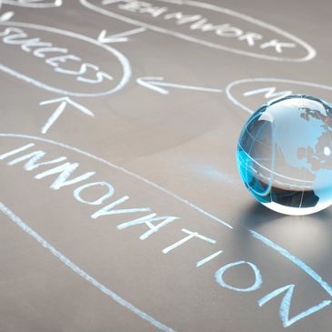 A glass globe on a chalkboard with business strategy keywords like innovation and success.