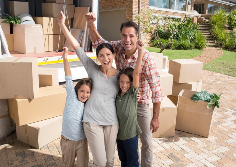 Portrait of family cheering near moving van in driveway