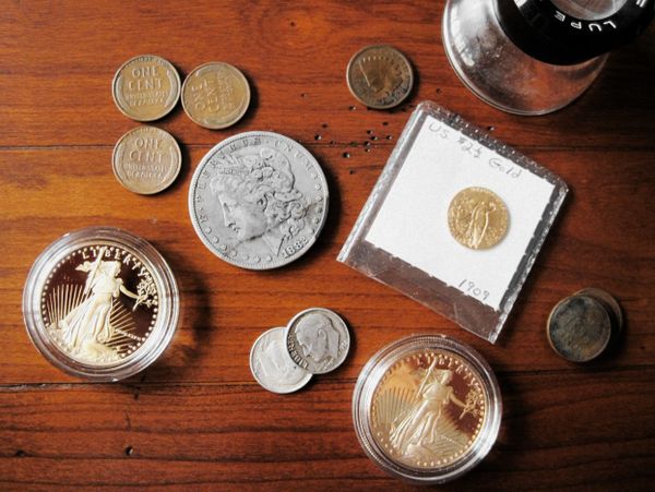 A collection of various old and gold coins on a wooden table.