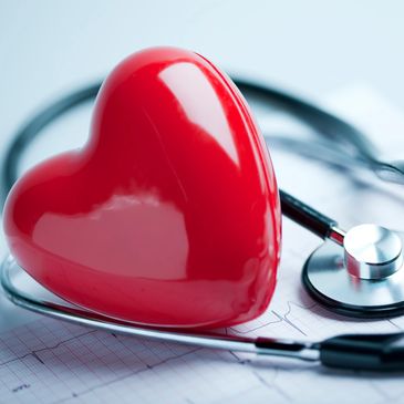 Red heart model and stethoscope on ECG paper symbolizing heart health.