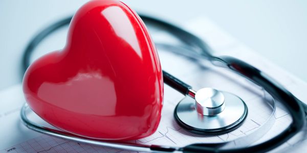 Red heart and stethoscope on medical paper.