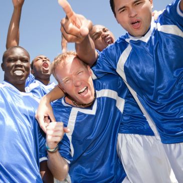 Excited soccer players celebrating a victory together outdoors.