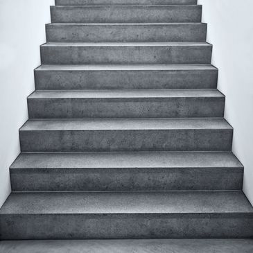Minimalist concrete stairs ascending against a white wall.