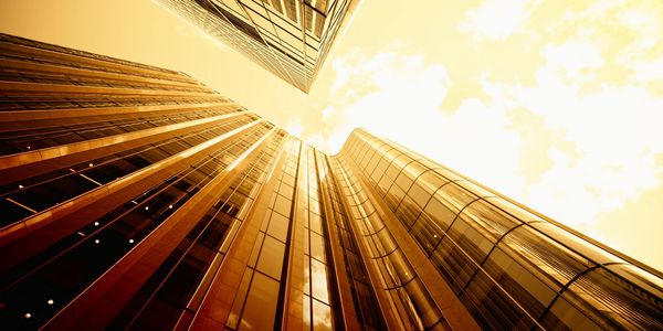 Looking up at modern skyscrapers with warm golden tones.