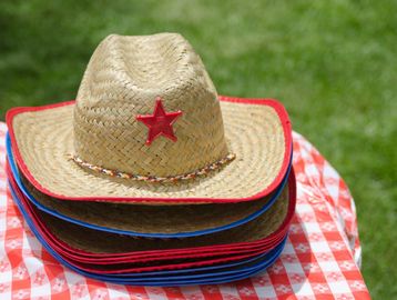 Stack of straw cowboy hats with red star on a picnic table.