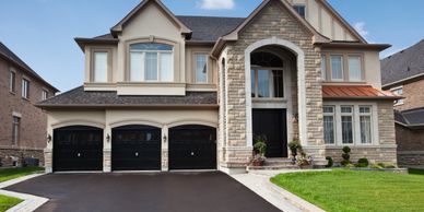 Large modern house with three-car garage and stone facade.