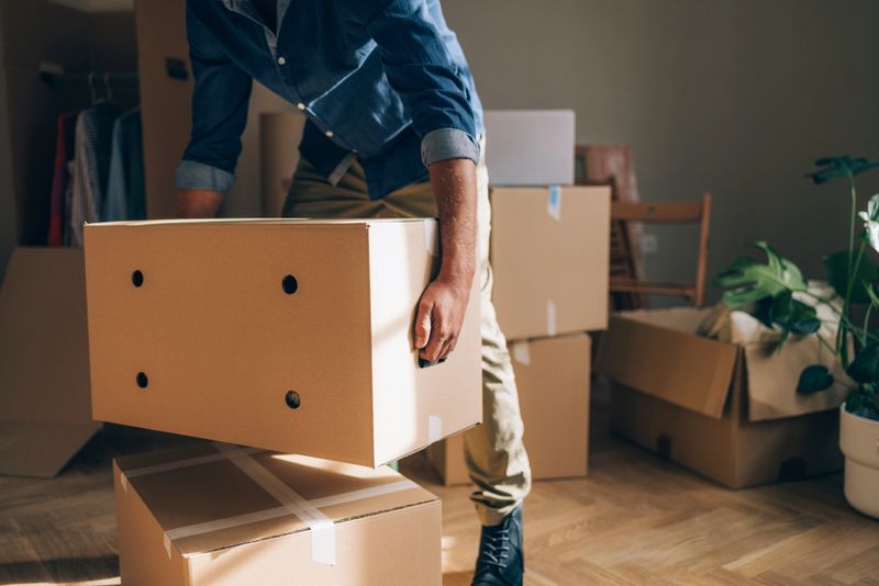 Man moves into his new home, arranging belongings and embracing the journey of creating his own space.