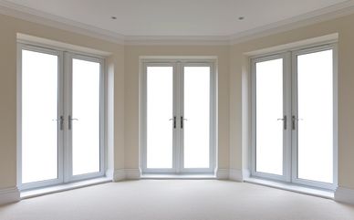 Three sets of white double glass doors in a beige room.