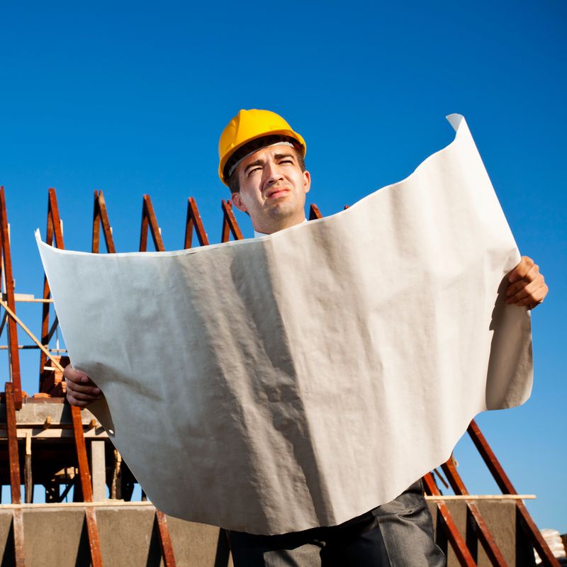 Construction architect reviews plans at a construction site.