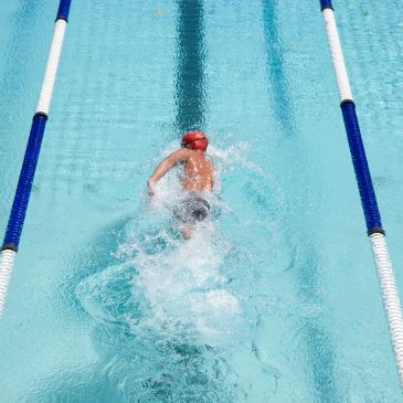 A swimmer in a red cap swimming in a lane pool.