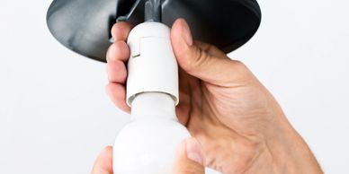 Hand screwing a white LED bulb into a socket.