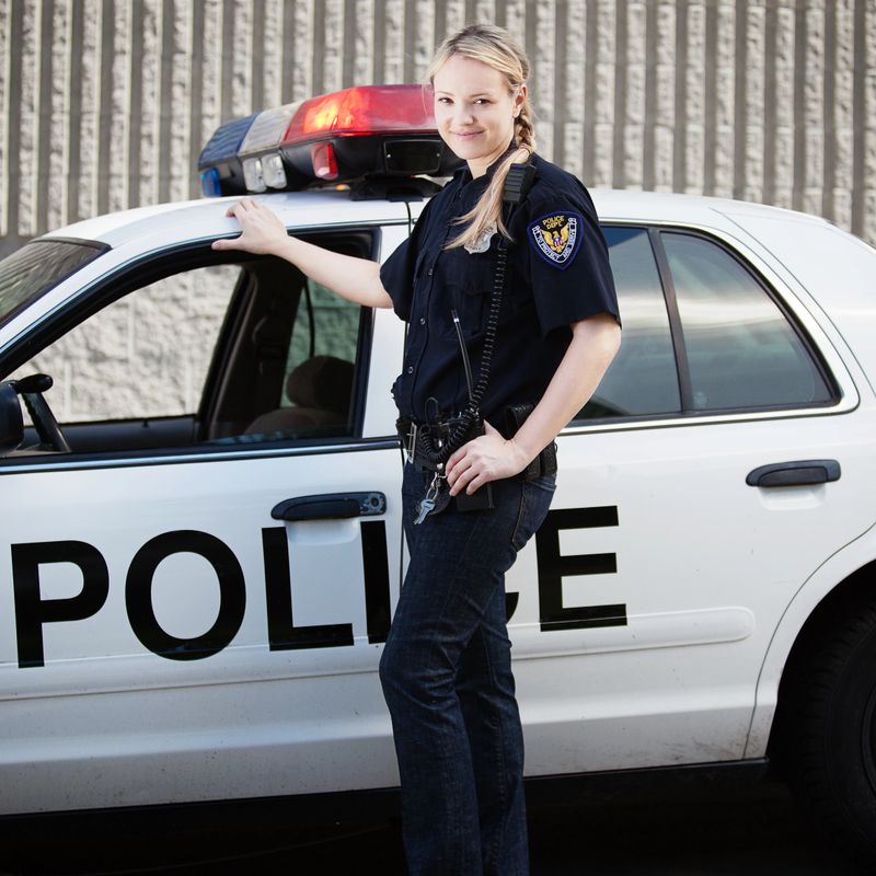 Friendly looking police officer in front of police car