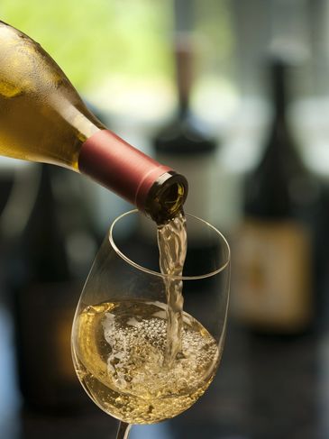 White wine being poured into a glass from a bottle.