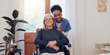 Caregiver embraces elderly woman in wheelchair inside a cozy home.