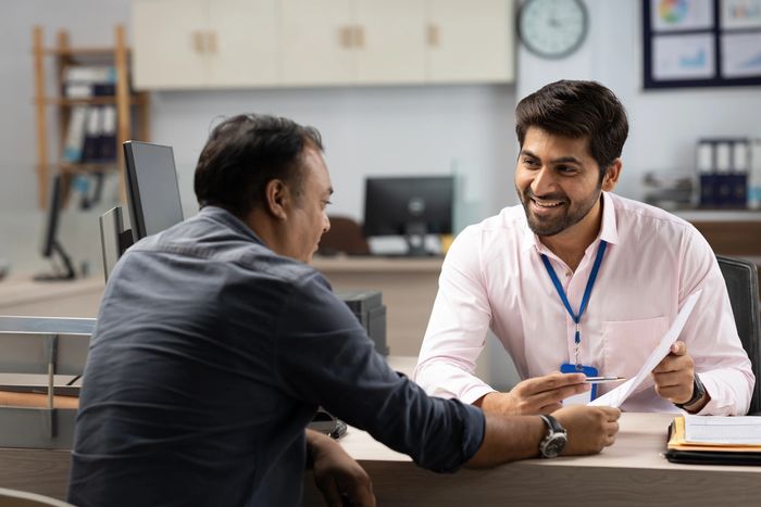Tax consultant explaining income tax and GST filing to a business client at his office desk