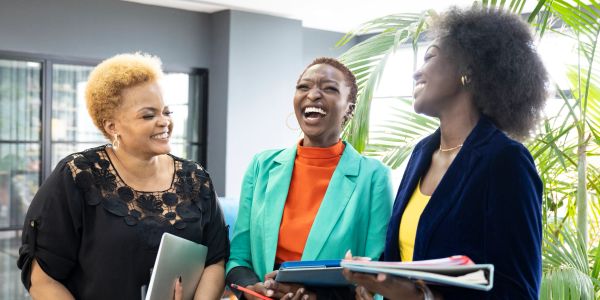 Three professional women happily discussing work.