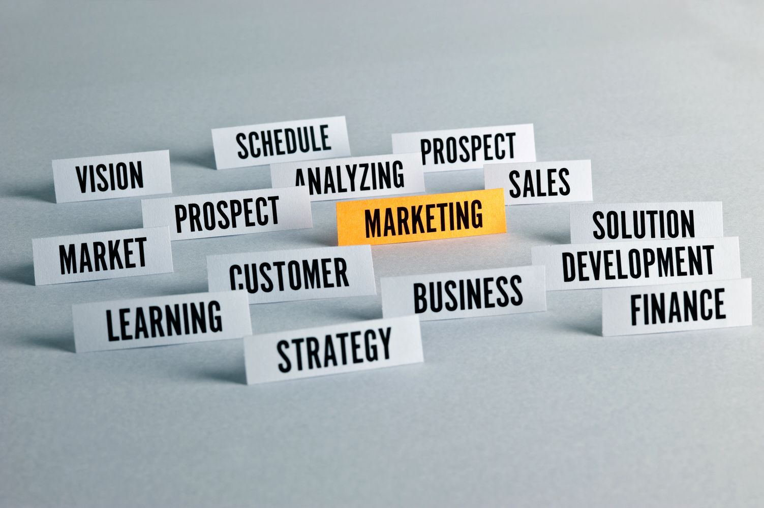 Business and marketing related words on cards with marketing highlighted in orange.