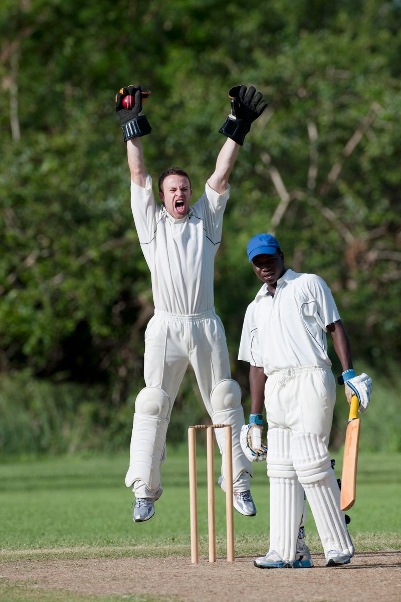 "Cricket action, wicketkeeper appealing for a wicket after catching the ball."
