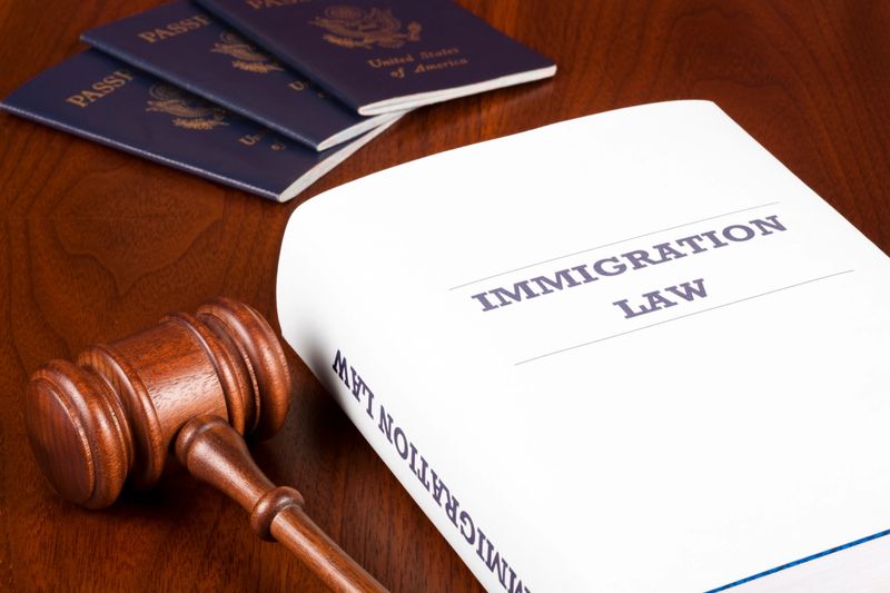 Three US passports and gavel next to Immigration Law handbook.