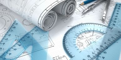Engineering blueprints with drafting tools and rulers on a workspace.
