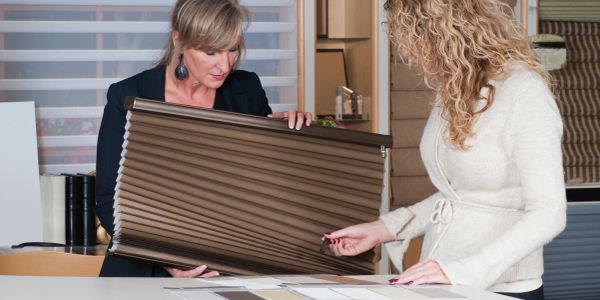 Two women examining window blind samples in a showroom.