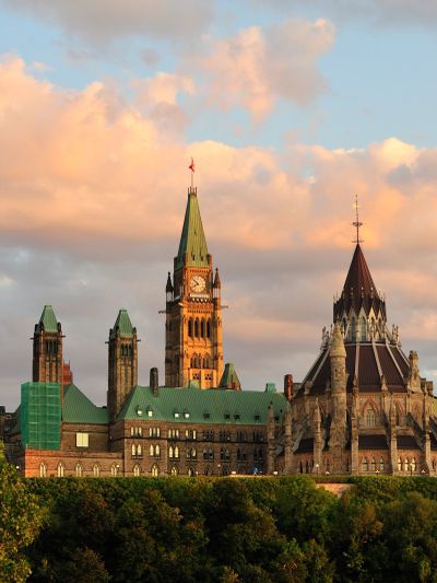 Historic parliament building with a clock tower at sunset.