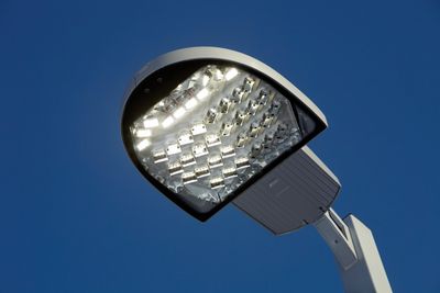 Close-up of a modern LED street light against a clear blue sky.