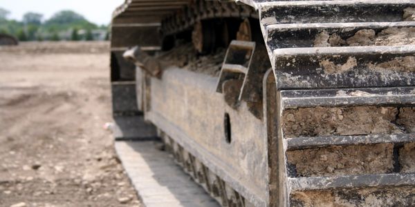 Close-up of a dirt-covered tank track on a muddy terrain.